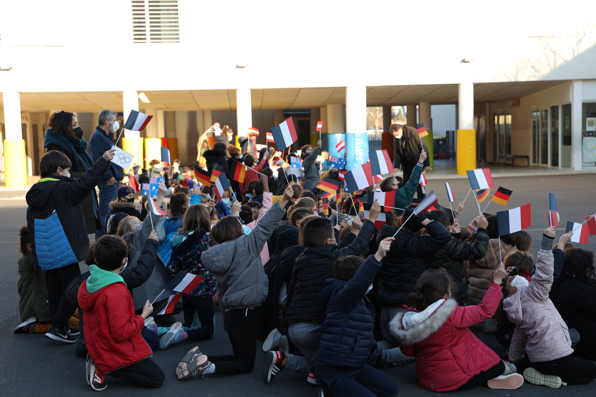 Les enfants sont assis dans la cour de récréation, tenant des drapeaux.