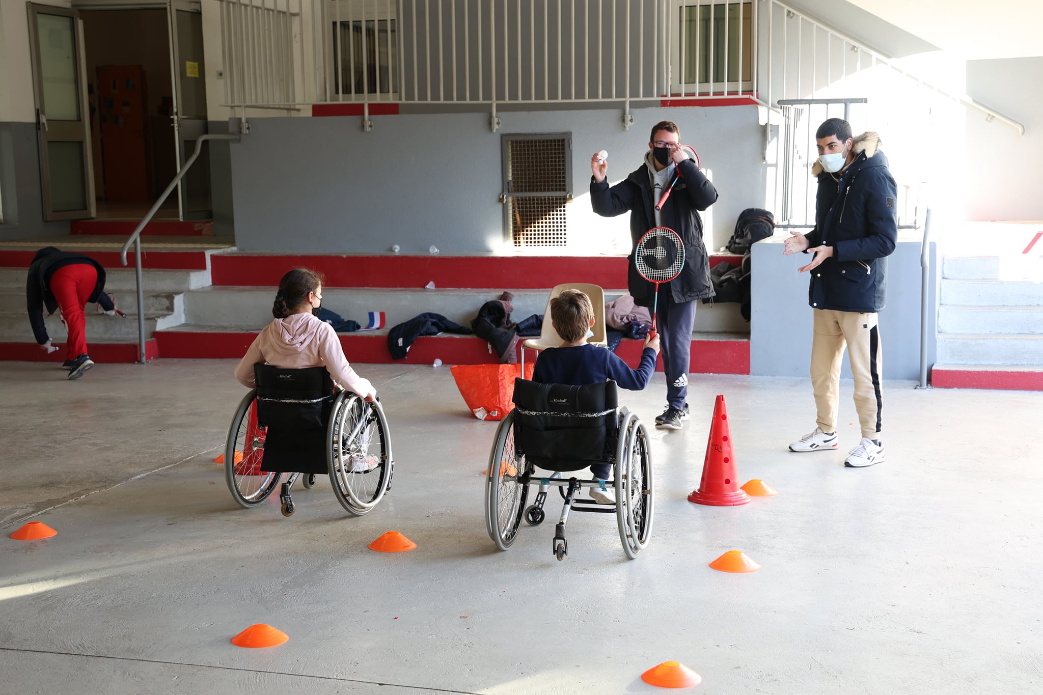 Deux enfants en fauteuil roulant jouent au badminton.