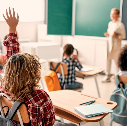 Des élèves dont un qui lève la main en classe