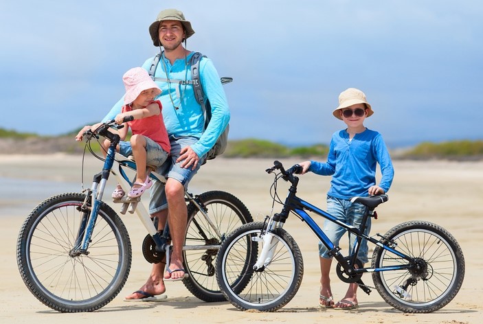 Un père et ses deux enfants à vélo