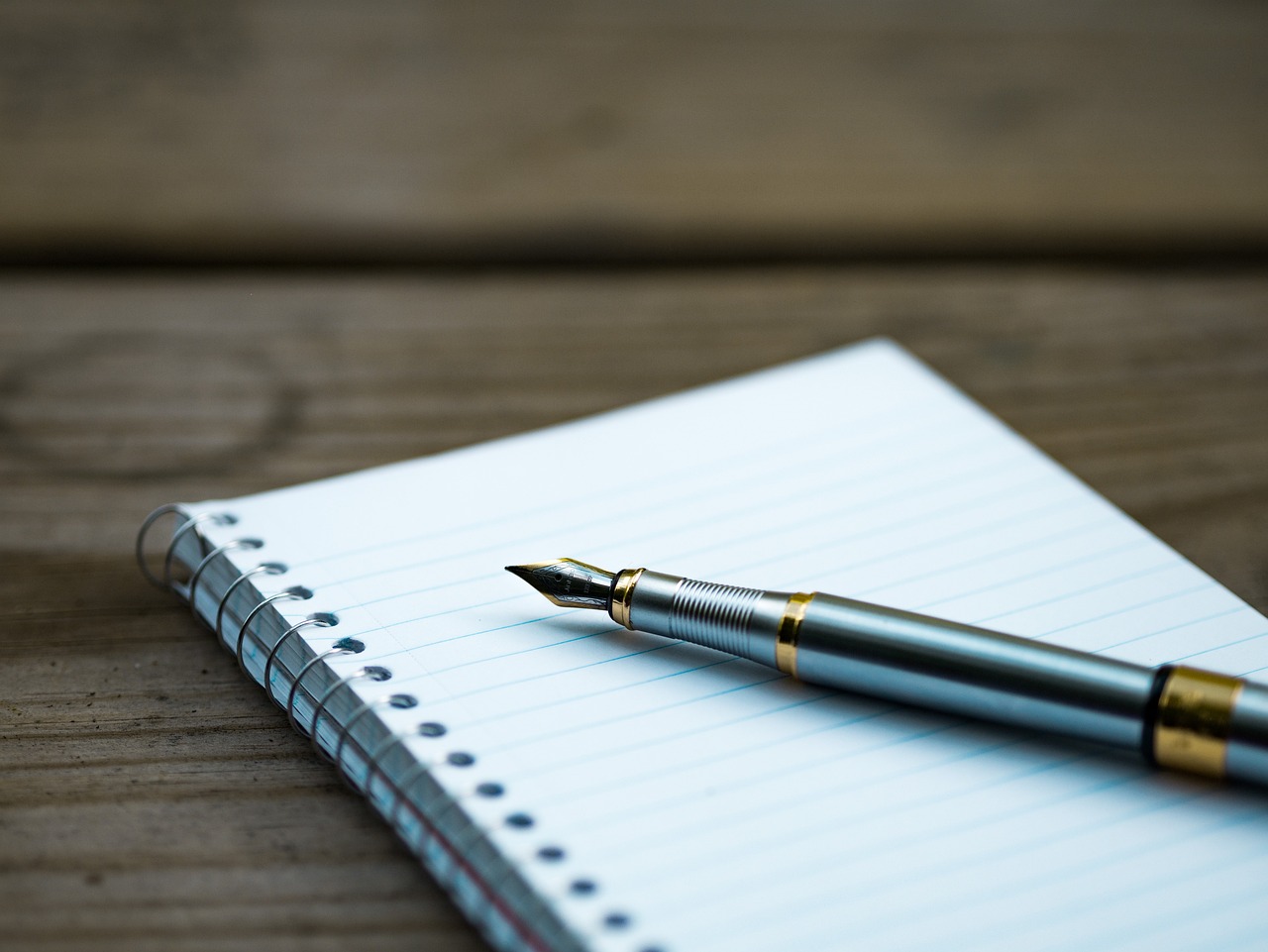 Un stylo plume et un carnet posés sur un bureau