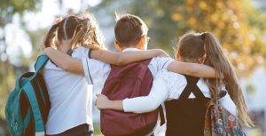 Des enfants munis de sacs à dos, vus de derrière