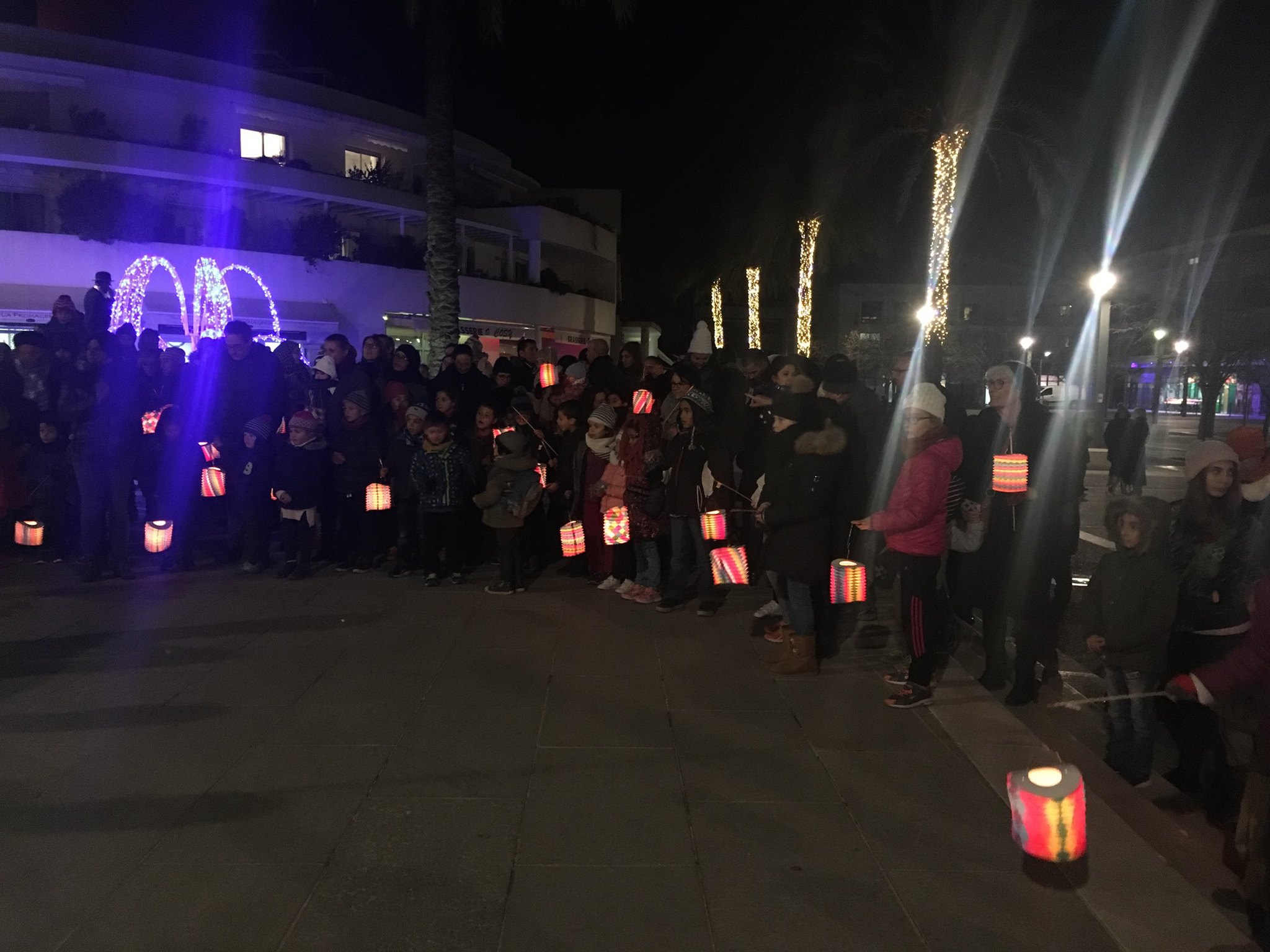 Une foule tenant des lampions à la main, devant la mairie de Castelnau