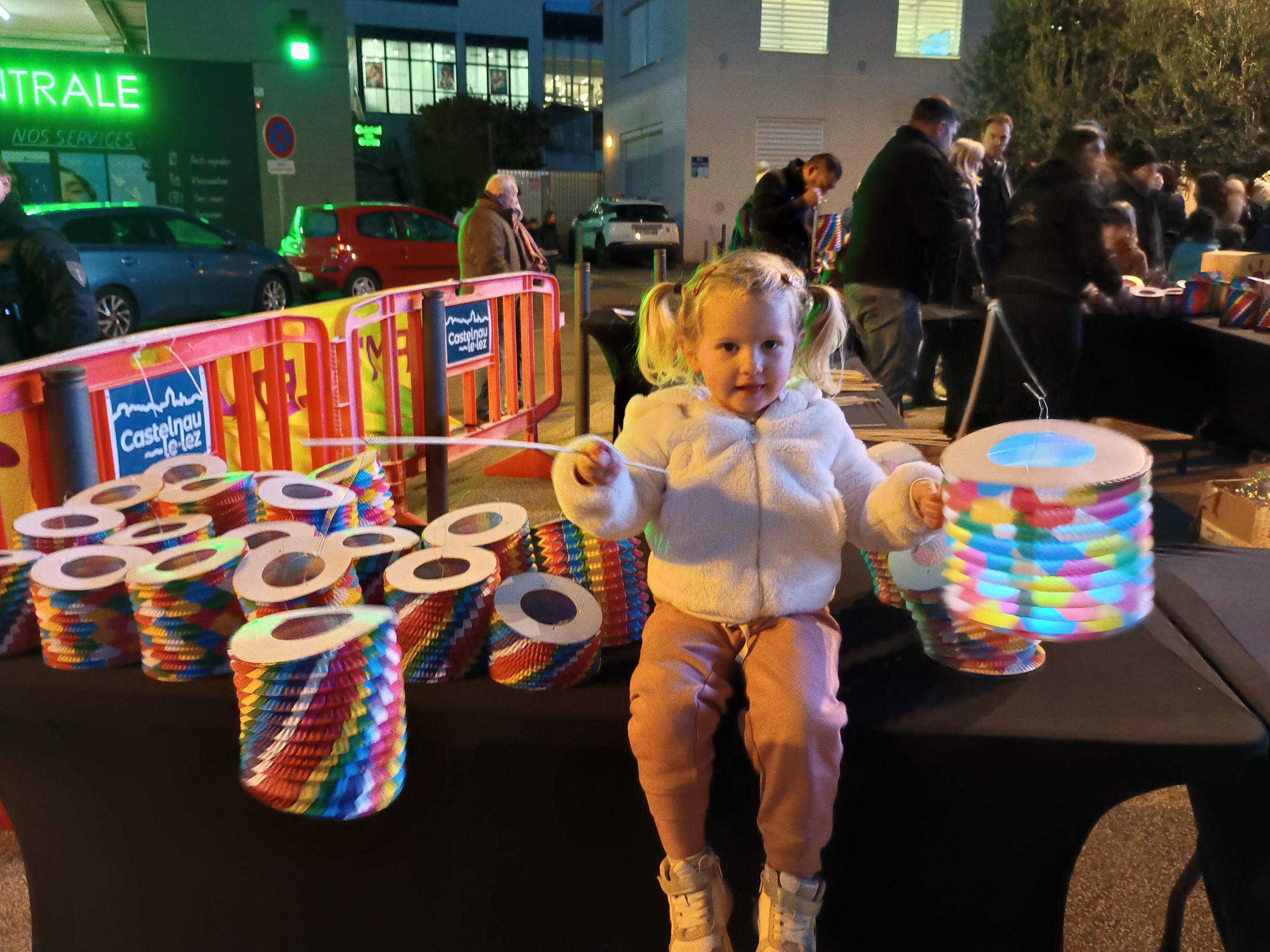 Une petite fille blonde qui tient dans chaque main un lampion lumineux