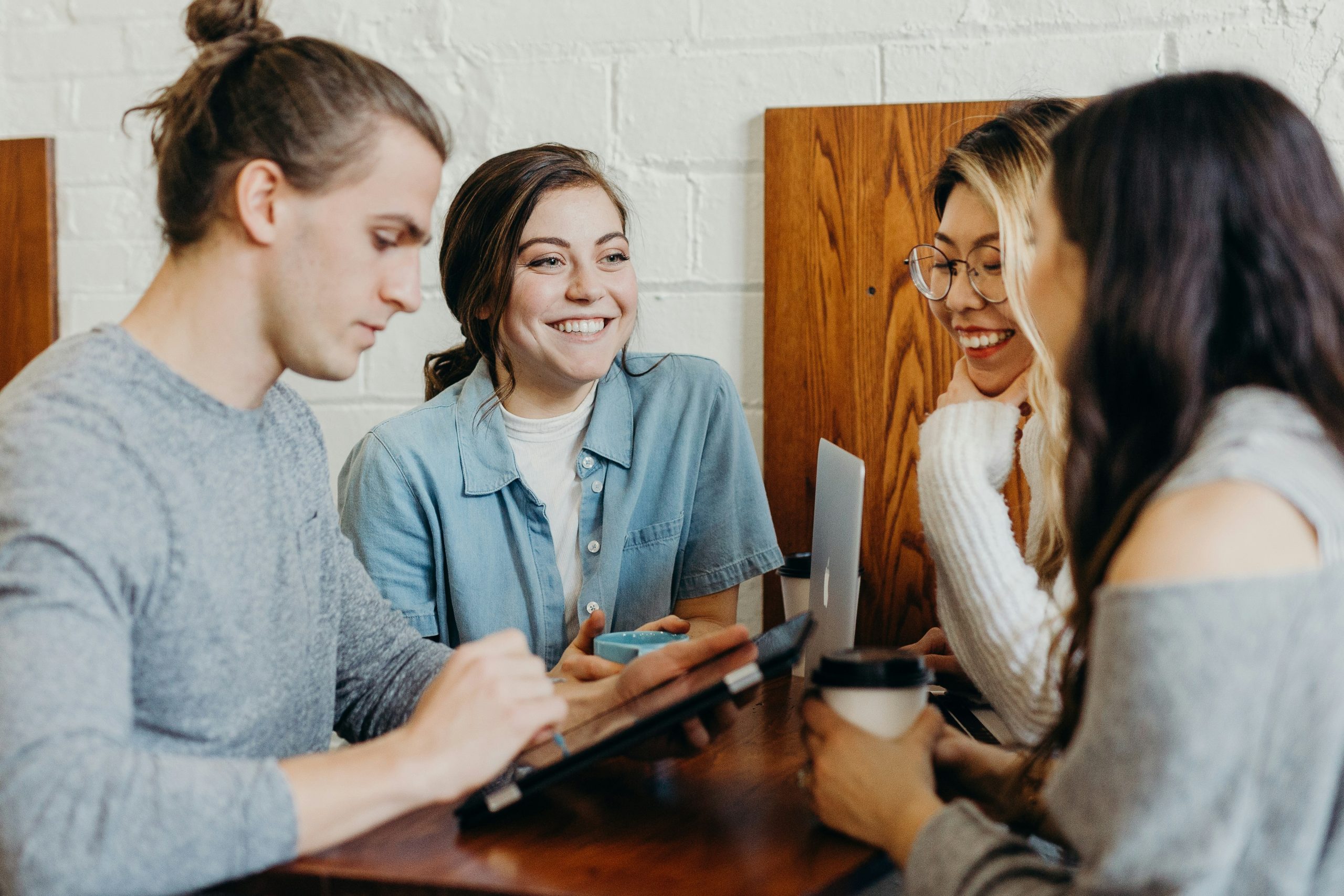 Des étudiantes et étudiants autour d'une table avec tablette et ordinateur portable