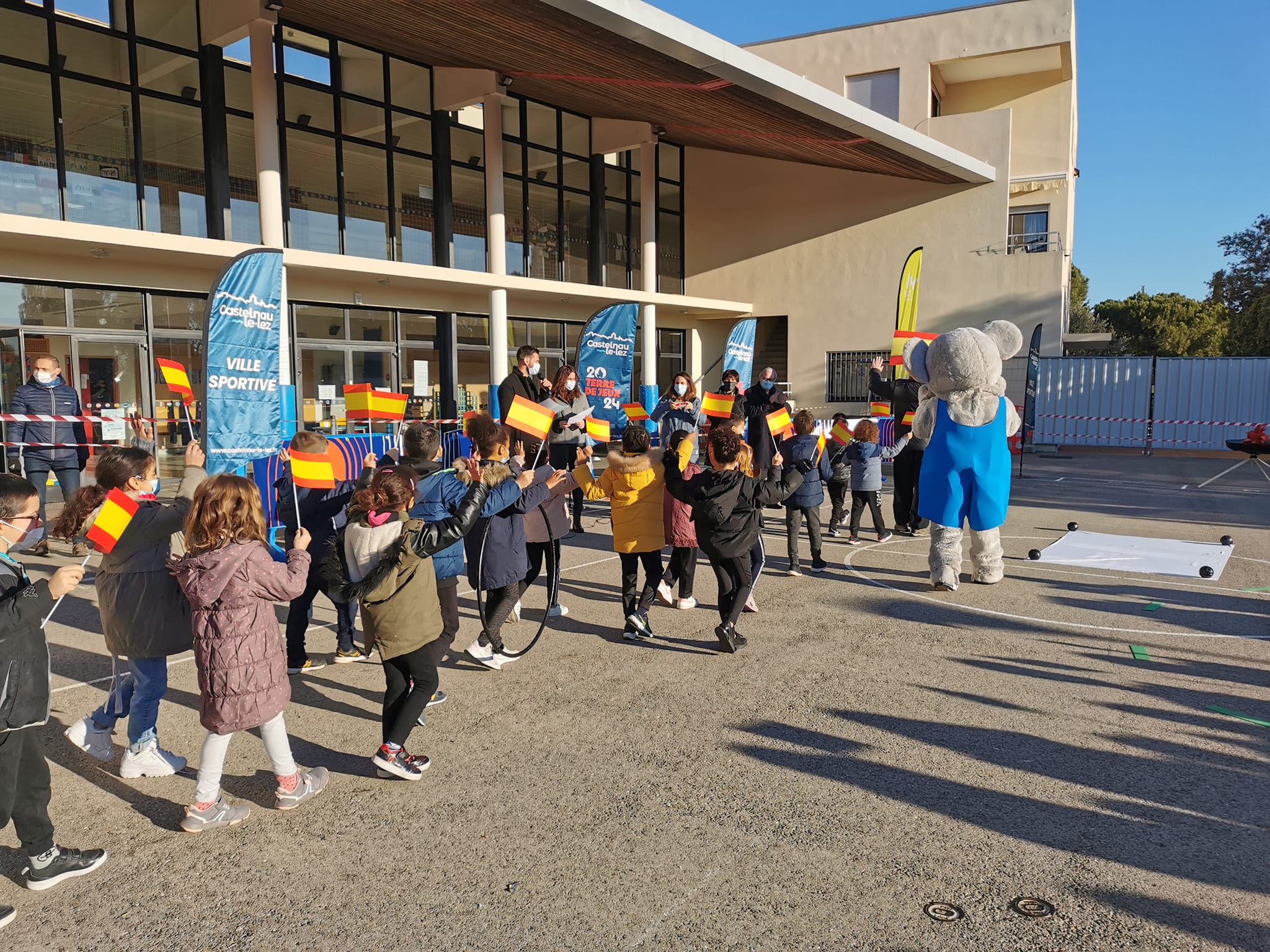 Un groupe d'enfants tiennent des drapeaux de l'Espagne, en marchant à l'arrière de la mascotte.